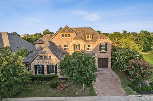 French provincial home featuring stone siding, concrete driveway, a garage, and brick siding | Image 24