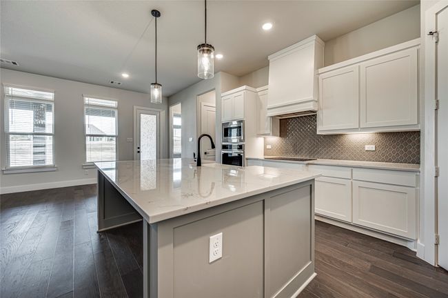 Kitchen with tasteful backsplash, white cabinetry, dark wood-type flooring, and stainless steel appliances | Image 6