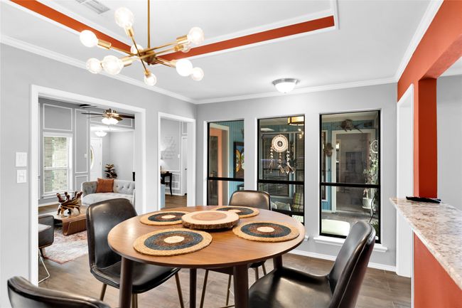 Dining room with dark wood-style flooring, crown molding, a chandelier, and a ceiling fan | Image 17
