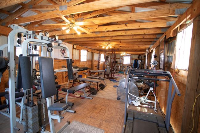Workout area with wood finished floors, ceiling fan, and lofted ceiling | Image 30