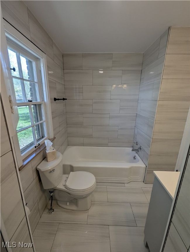 Full bathroom with vanity, tile patterned flooring, toilet, and shower / washtub combination | Image 13