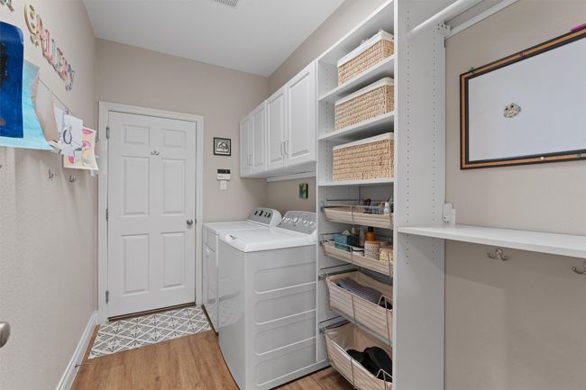 Laundry area featuring cabinet space and light wood finished floors. | Image 13