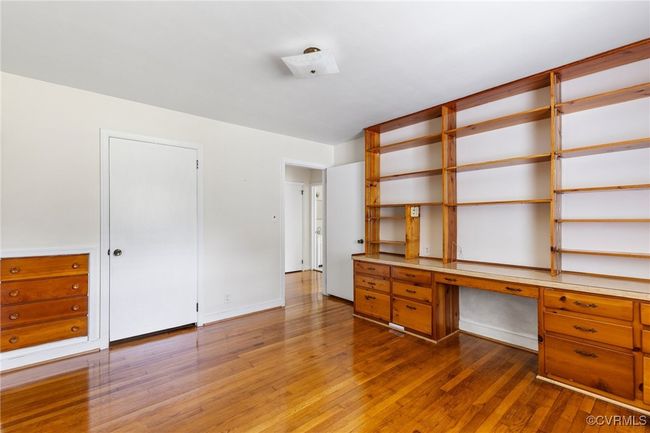 Unfurnished office with baseboards, built in study area, and wood-type flooring | Image 17