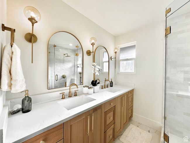 Full bath featuring double vanity, a stall shower, and marble look tiles | Image 21