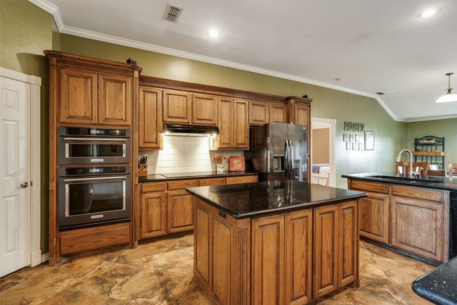Kitchen with visible vents, a sink, brown cabinets, and black appliances | Image 8