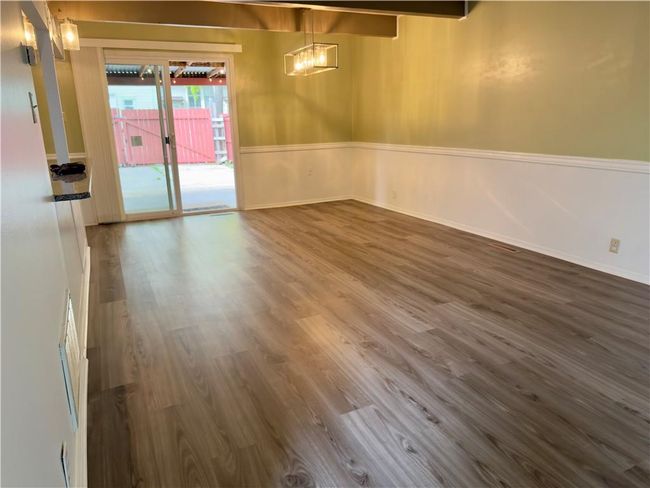 Unfurnished dining area with dark wood finished floors, baseboards, and a chandelier | Image 6