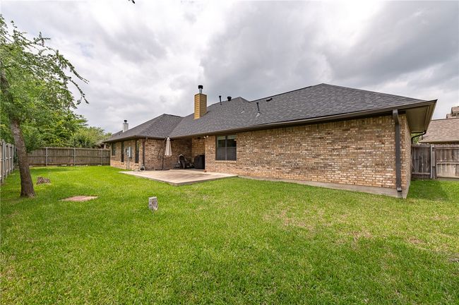 Rear view of house with a chimney, a patio area, a fenced backyard, and brick siding | Image 28