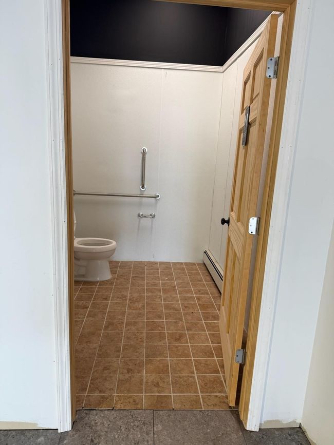 Bathroom with a baseboard radiator, tile patterned floors, and toilet | Image 8