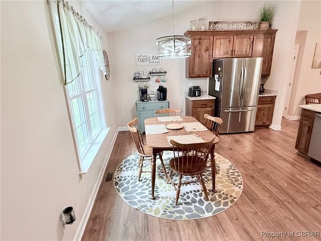 Dining space featuring light wood-style flooring, lofted ceiling, baseboards, and a chandelier. | Image 5