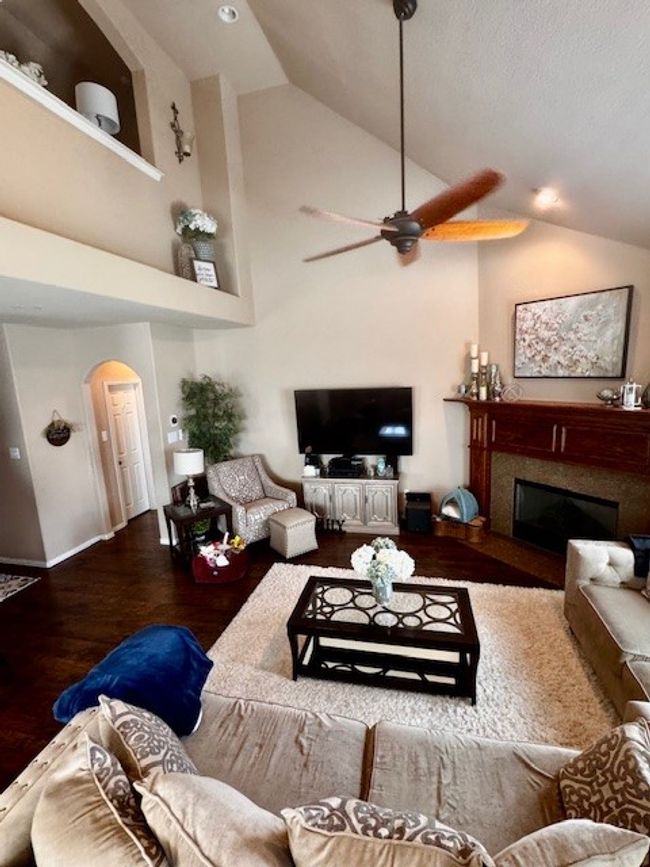 Living area featuring baseboards, arched walkways, a ceiling fan, wood finished floors, and a glass covered fireplace | Image 8