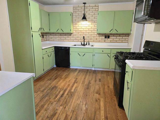 Kitchen featuring green cabinetry, sink, and black appliances | Image 7