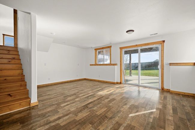 Unfurnished living room with wood finished floors, baseboards, and stairway | Image 12