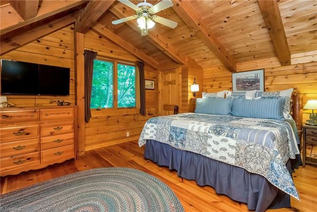 The basement-level den in the log cabin beckons with picturesque mountain views and French doors leading out to a charming outdoor area adorned with two swings, creating a serene retreat immersed in the beauty of nature. | Image 40