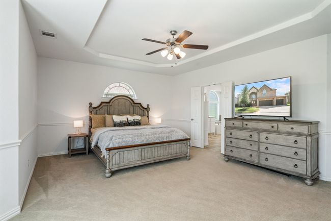 Bedroom with a tray ceiling, light carpet, ceiling fan, and connected bathroom | Image 21