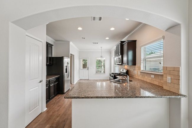 Kitchen with stainless steel appliances, crown molding, dark stone counters, healthy amount of natural light, and tasteful backsplash | Image 11