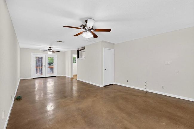 Unfurnished living room featuring concrete flooring, a ceiling fan, and baseboards | Image 10