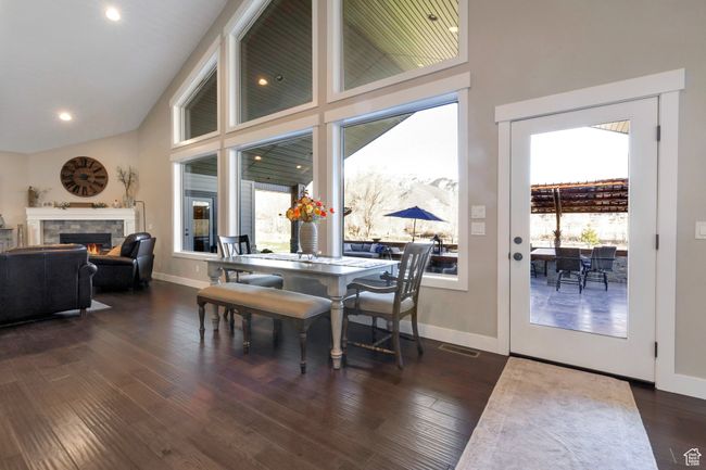 Dining area with dark wood-type flooring, baseboards, a high ceiling, and a fireplace | Image 8