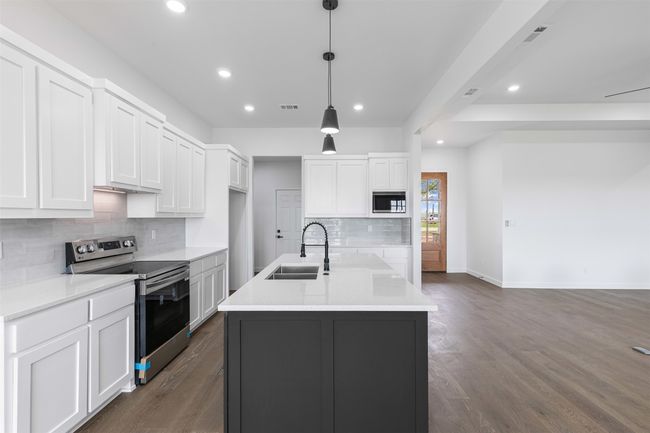 Kitchen with backsplash, appliances with stainless steel finishes, a sink, baseboards, and recessed lighting | Image 16
