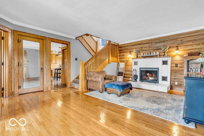 living room featuring wood-type flooring, stairs, a brick fireplace, and ornamental molding | Image 18