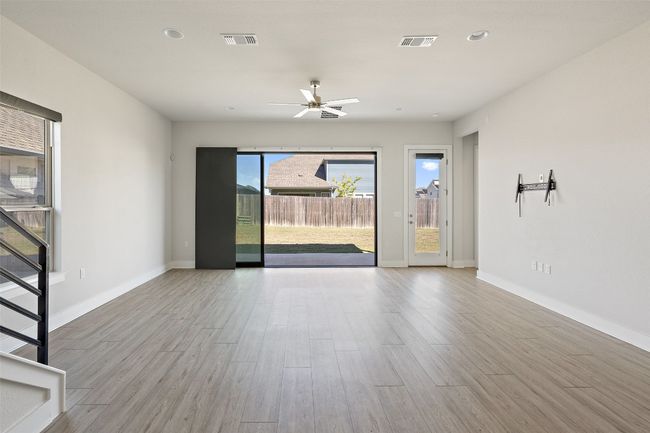 Empty room featuring wood finished floors, a ceiling fan, and stairway | Image 6