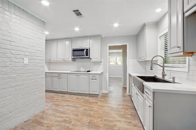 The heart of the home is fully updated with durable quartz counters, stylish cabinetry, and brand-new stainless steel appliances that bring a polished look to every detail. | Image 11