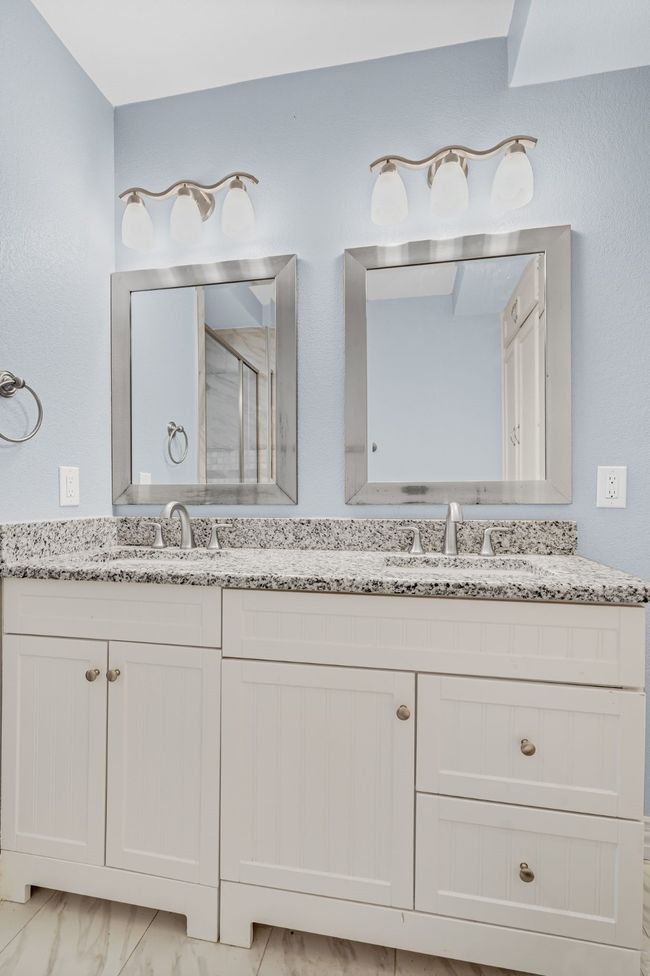 Bathroom with double vanity, a shower stall, and marble look tiles | Image 15