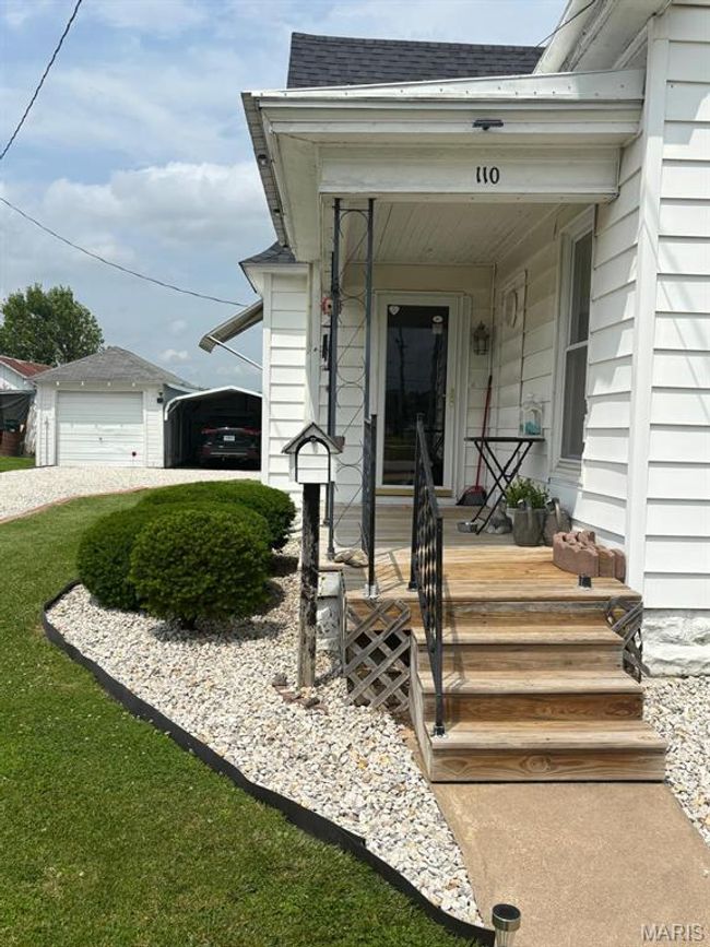 Doorway to property featuring roof with shingles, a porch, and a detached garage | Image 4