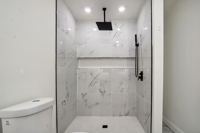 Bathroom with marble finish floor, a shower stall, toilet, and baseboards | Image 18