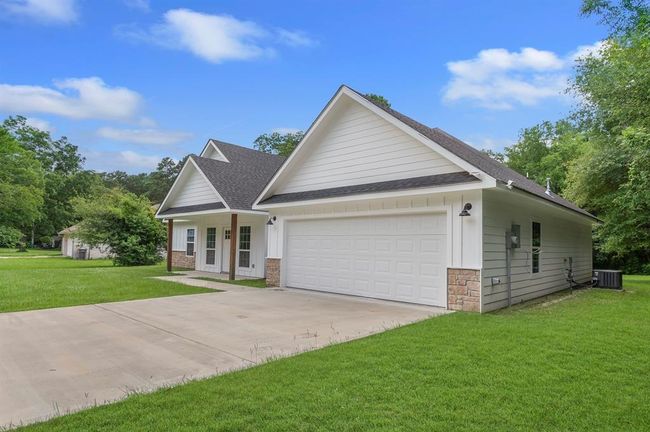 Charming single-story home with a modern design, featuring a spacious two-car garage, clean siding, and stone accents. It sits on a well-maintained grassy lot with mature trees, offering a peaceful and inviting atmosphere. | Image 22