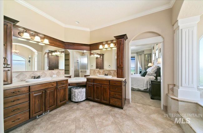 Ensuite bathroom with decorative columns, two vanities, a chandelier, backsplash, and crown molding | Image 19