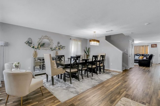 Dining area featuring baseboards, stairs, an inviting chandelier, and wood finished floors | Image 4