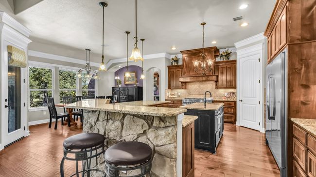 Kitchen featuring an island with sink, stainless steel refrigerator, arched walkways, decorative backsplash, and hardwood / wood-style floors | Image 20