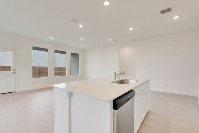 Kitchen featuring stainless steel dishwasher, a sink, light wood-style flooring, white cabinets, and light countertops | Image 8