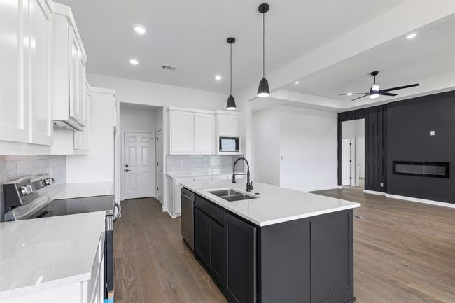 Kitchen featuring visible vents, wood finished floors, tasteful backsplash, a sink, and appliances with stainless steel finishes | Image 17