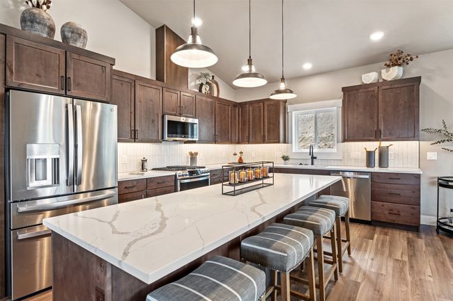 Kitchen with appliances with stainless steel finishes, a sink, a breakfast bar area, a center island, and decorative backsplash | Image 45