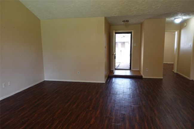 Inviting front entryway opens into a spacious living room, showcasing beautiful flooring and ample natural light. | Image 20