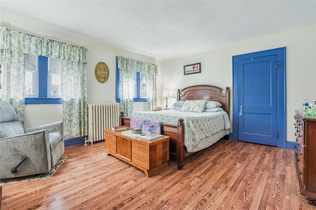 Bedroom featuring radiator heating unit, ornamental molding, and wood finished floors | Image 20