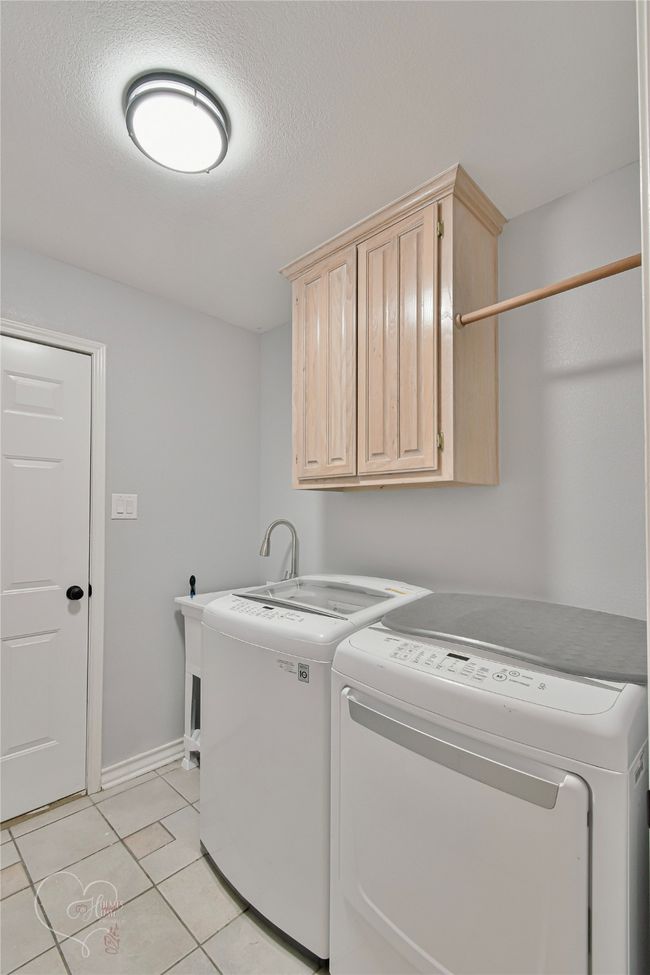 Laundry area with cabinet space, independent washer and dryer, and light tile patterned flooring | Image 18
