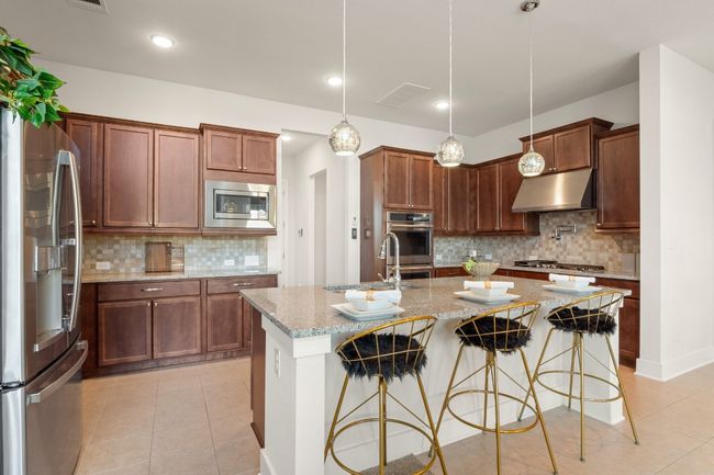 Kitchen with a sink, backsplash, appliances with stainless steel finishes, under cabinet range hood, and light tile patterned floors | Image 10
