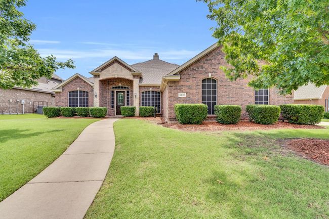 French country inspired facade featuring brick siding, a shingled roof, and a chimney | Image 35