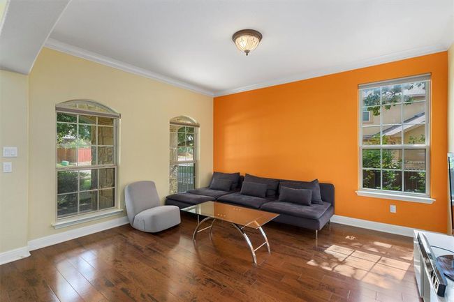 Living area featuring healthy amount of natural light, wood-type flooring, baseboards, and crown molding | Image 7