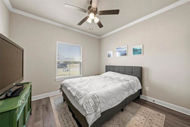 Bedroom with a ceiling fan, ornamental molding, baseboards, and dark wood-style floors | Image 17