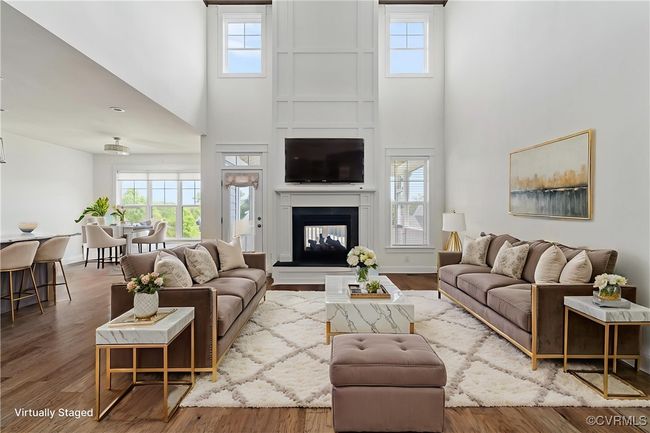 Living room featuring a towering ceiling, healthy amount of natural light, a multi sided fireplace, and wood finished floors | Image 6