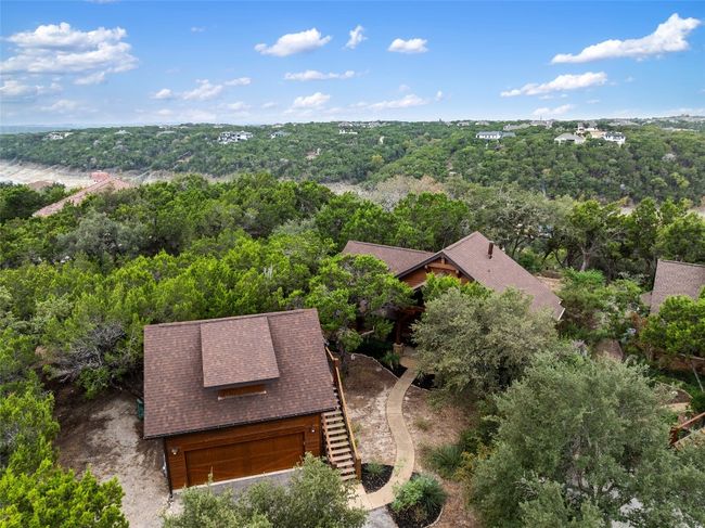 This aerial view captures the property's natural surroundings, nestled among lush trees with scenic hill views in the background. | Image 32