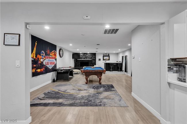 Recreation room with a fireplace, visible vents, billiards, and light wood-style flooring | Image 15