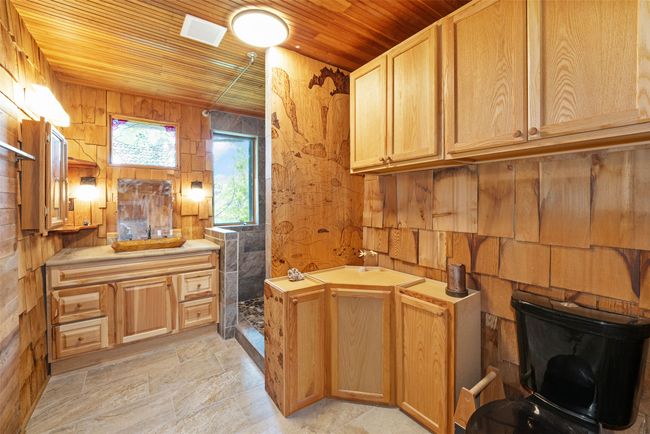 Full bath featuring wooden ceiling, vanity, wooden walls, and tiled shower | Image 21