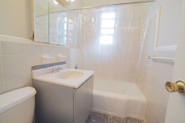 Full bathroom with tile walls, vanity, and shower / tub combo with curtain | Image 5