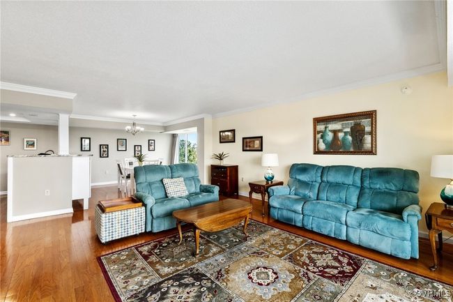 Living area featuring ornamental molding, wood finished floors, a chandelier, and baseboards | Image 5
