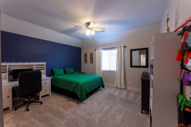 Bedroom featuring light colored carpet, a ceiling fan, and a desk | Image 31