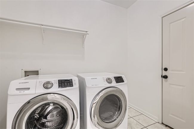 Laundry room featuring washer and dryer, light tile patterned floors, and baseboards | Image 37